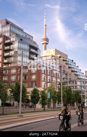 Toronto, Ontario, Canada - 2019 0609 Les Torontois : profiter d'un programme de partage de vélo randonnée à vélo le long de la Queens Quay en face d'une tour résidentielle Banque D'Images