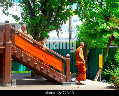 Les moines descendant quelques marches d'un temple dans leurs robes orange après la prière au temple de Chalong Phuket Thaïlande Banque D'Images