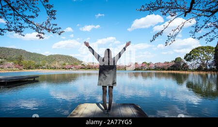 Jeune femme jouissant de la liberté avec les mains ouvertes en face du lac avec la nature paysage pendant le printemps ! Banque D'Images