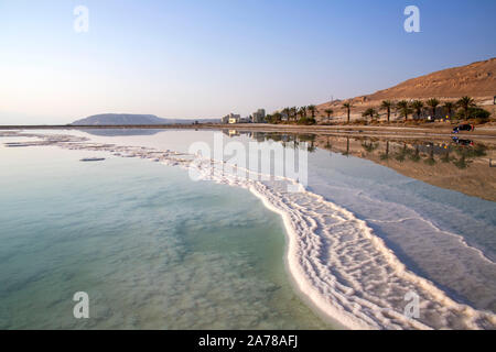 Reflet de la montagne et de palmiers dans l'eau de la Mer Morte avec du sel formations. Israël Banque D'Images