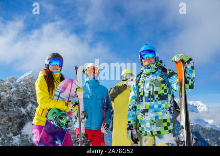 Trois hommes et une femme avec un snowboard et skis de neige sur la montagne de la station et ciel nuageux en après-midi Banque D'Images