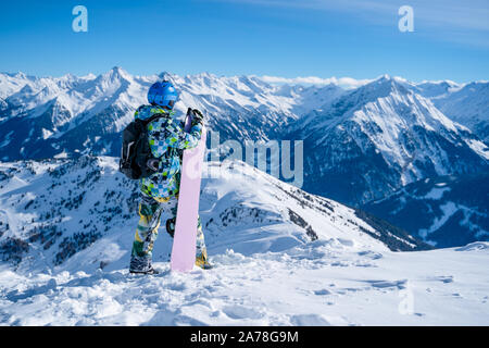 Photo de l'arrière de l'homme sportif en casque avec la planche à neige ski resort Banque D'Images