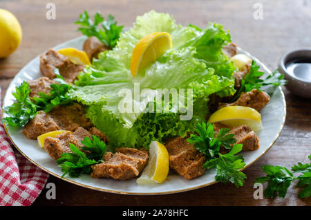 La nourriture turque : Cig Kofte avec le citron, l'assaisonnement, la laitue et le persil. Banque D'Images