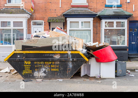 Ordures débordant à l'extérieur skip to un étudiant maison mitoyenne à Selly Oak, Birmingham, UK Banque D'Images