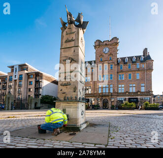 Tower Place, Leith, Edinburgh, Ecosse, Royaume-Uni, le 31 octobre 2019. Nettoyer pour la marine marchande écossais. Memorial avec Malmaison Hotel, ancien Leith Seamen's Mission. Brian Caster, Directeur de Powderhall Bronze fonderie, ce qui jette le mémorial, lui donne une propre dans la préparation d'une cérémonie le 11 novembre pour se souvenir des milliers de marins marchands écossais qui sont morts pendant les guerres. Le monument par le sculpteur Jill Watson est un hommage aux gens de mer et les pêcheurs écossais. ici, c'est pas de budget pour l'entretien du monument, mais la fonderie s'engage le travail comme le monument est spécial d'e Banque D'Images