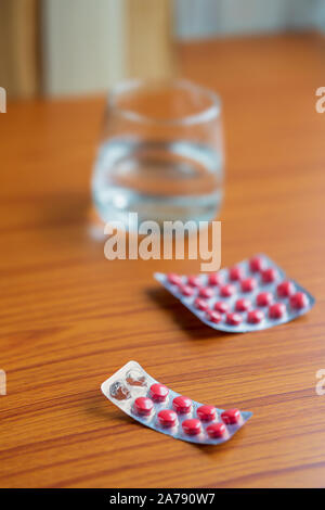 Antibiotiques pharmaceutiques comprimés et gélules pour patient sur un bureau en bois brun à la maison. Concept de base de la médecine et de la santé. Banque D'Images