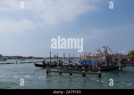 Scène traditionnelle de l'eau de Venise avec de nombreuses gondoles amarré jusqu'entre les poteaux. Grand ciel au soleil. Banque D'Images