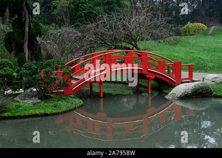 Vue d'un pont rouge au-dessus d'un lac artificiel à Pierre Baudis Jardin Japonais, un parc public de style japonais, à Toulouse, France Banque D'Images