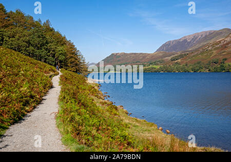 Les gens qui marchent le long de sentier de promenade à côté de Buttermere en automne Lake District National Park Cumbria Angleterre Royaume-Uni Grande-Bretagne Banque D'Images