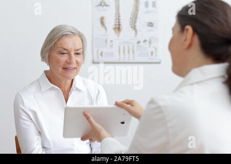 Technologie concept de soins de santé : médecin généraliste en montrant son patient smiling senior résultats de laboratoire sur un tablet pc. Banque D'Images