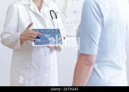 Concept de prévention des AVC : doctor with tablet pc montrant son patient d'une ERM libre de ses vaisseaux sanguins cérébraux. Banque D'Images