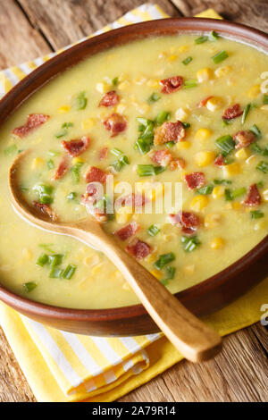 Chaudrée de maïs soupe d'hiver avec bacon et oignons verts close-up dans une assiette sur la table verticale. Banque D'Images