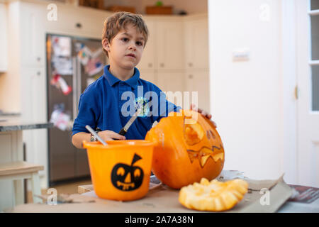 Un garçon de 6 ans qui a racé la croûte à l'intérieur d'une citrouille sculptée avant Halloween, Angleterre, Royaume-Uni Banque D'Images