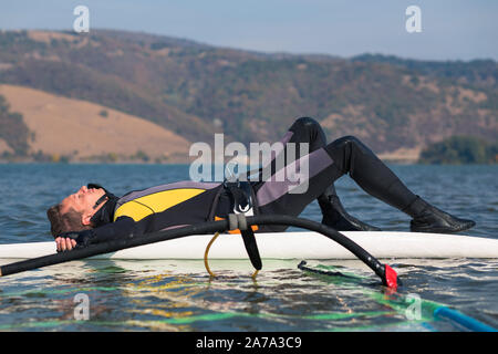 Jeune windsurfer en appui sur une planche de surf dans l'océan. Sport et loisirs concept. Banque D'Images