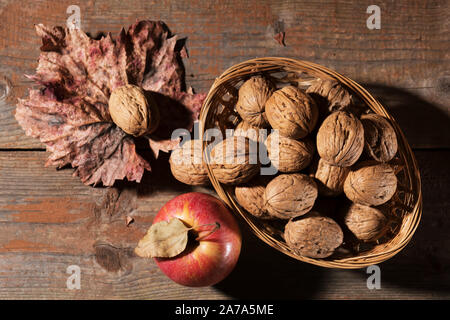 Les noix entières avec Apple sur la vieille table en bois rustique. L'alimentation saine, gras sain, farvest automne arrière-plan. La récolte de l'automne beauté concept. Automne compositi Banque D'Images