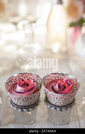 Une belle composition de rose rose et cup cakes sur une table de luxe Banque D'Images