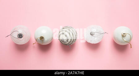 Décoration de Noël. Xmas boules de couleur blanche, variété d'affilée contre fond rose pastel Banque D'Images