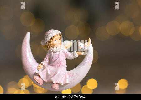 Figurines décoratives d'un thème de Noël. Statuette d'un ange sur un croissant de lune. Décoration d'arbre de Noël. Décor de fête, chaud bokeh lights Banque D'Images