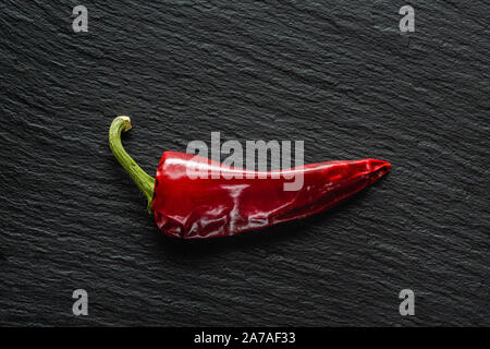 Seul le poivre rouge banane séchée sur une ardoise gris foncé with copy space Banque D'Images