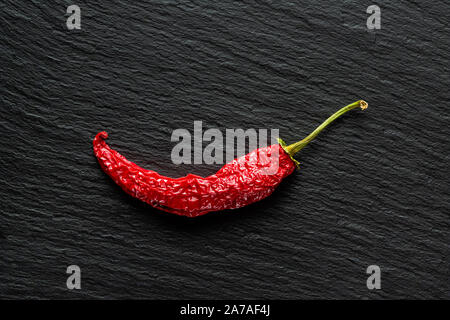 Seul le poivre rouge banane séchée sur une ardoise gris foncé with copy space Banque D'Images