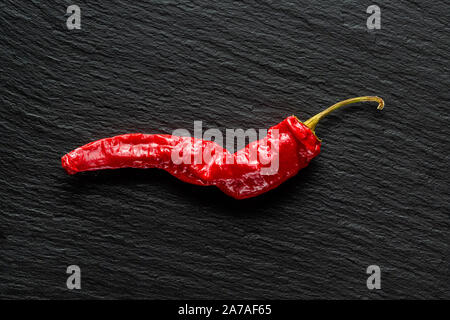 Seul le poivre rouge banane séchée sur une ardoise gris foncé with copy space Banque D'Images