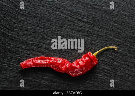 Seul le poivre rouge banane séchée sur une ardoise gris foncé with copy space Banque D'Images