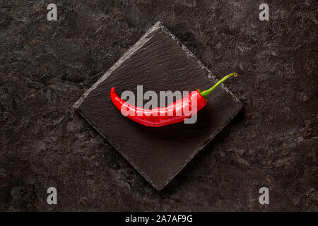 Seul le poivre rouge banane séchée sur une ardoise gris foncé Banque D'Images