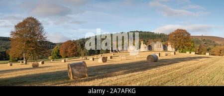 Une vue panoramique de Kildrummy Castle dans Aberdeenshire entouré par les arbres dans leur feuillage de l'automne et avec des bottes de paille en premier plan Banque D'Images