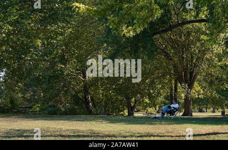 Arlington, VA / USA - 23 septembre 2019 : Caucasian man lit un livre à l'ombre un jour d'été Banque D'Images