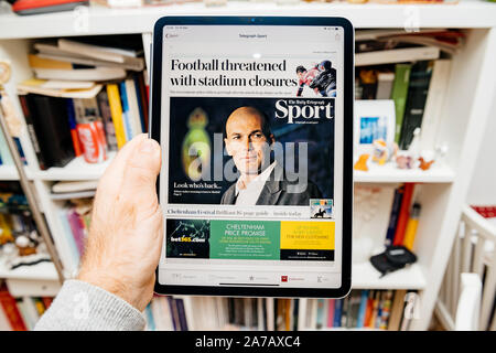 Paris, France - Nov 2, 2019 : Man hand holding tablet Ipad lire la version électronique du journal britannique The Daily Telegraph sport section sur Zinedine Zidane sur l'actualité Apple app Banque D'Images