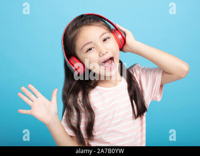 Happy little girl avec un casque à l'écoute et le chant chanson Banque D'Images