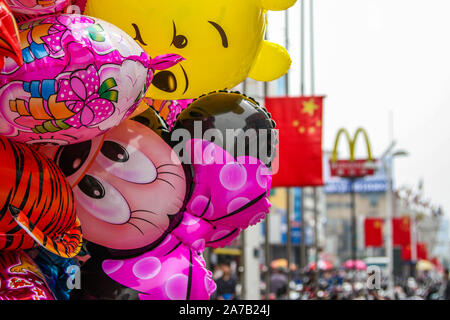 Personnages de dessins animés Disney ballon vu vendre dans les rues de Chongqing City, province de Jiangsu, Chine. Chine drapeau et le logo de McDonald's en arrière-plan. Banque D'Images