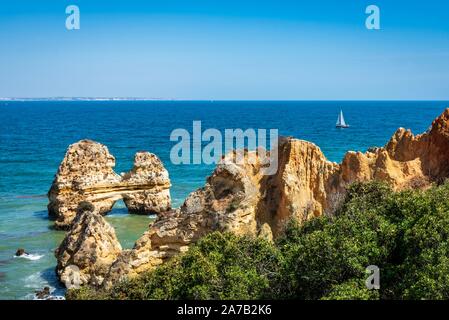 Bateau naviguant au-delà des piles de rochers et mer près de la plage Praia Dona Ana, au Portugal. Banque D'Images