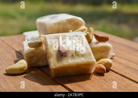 Sonpapdi et écrous sur table en bois,indienne forme cube/dessert croustillant de floconneux. Banque D'Images