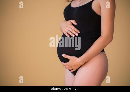 Ventre enceinte close up. Fille enceinte dans un élégant body noir. Belle grossesse en santé. Le minimalisme Banque D'Images