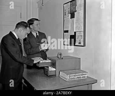 Les employés du Secret Service contrôle plus de tableau d'obtenir les dernières nouvelles de criminel ca. 1938 Banque D'Images