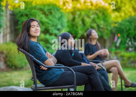 Amis assis sur des chaises de jardin en plein air de parler en été Banque D'Images