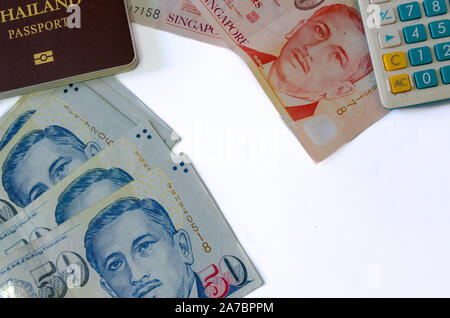 Cinquante dollars et dix dollars de Singapour et de passeports et calculatrices sur fond blanc Banque D'Images