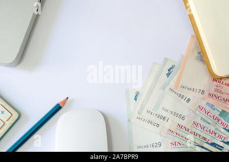 Cinquante dollars et dix dollars Singapour et de passeports et des calculatrices avec ordinateur portable sur un fond blanc Banque D'Images