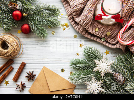 Mise à plat de la composition de Noël avec des branches de pins, bougie, enveloppes et décorations sur un fond de bois Banque D'Images