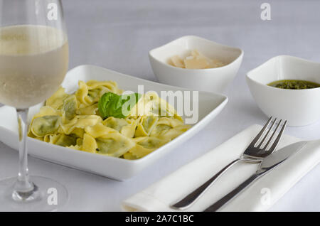 Ravioli italien rempli de fromage ricotta et épinards décoré avec du basilic, servi avec du parmesan et du pesto. Restaurant fond plat de pâtes. Banque D'Images