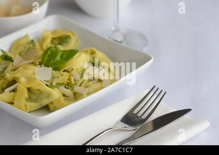 Ravioli italien rempli de fromage ricotta et épinards décoré avec du basilic, servi avec du parmesan et du pesto. Restaurant fond plat de pâtes. Banque D'Images