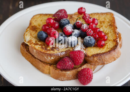 Pain doré fait maison avec des baies de cassis, bleuets, framboises et sucre à glacer pour un petit-déjeuner sucré. Délicieux dessert l'arrière-plan. Banque D'Images