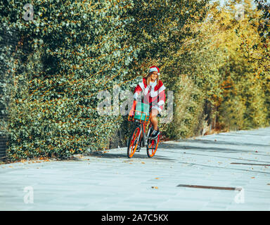 Stock photo de Mama noel avec son dos à la rue de la bicyclette. Temps de Noël Banque D'Images