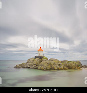 Un petit phare se dresse sur une île rocheuse au milieu de la mer. Banque D'Images