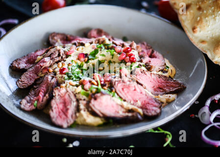 plat de houmous libanais avec bœuf rôti et graines de grenade Banque D'Images