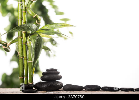 Grean sur des feuilles de bambou zen stones noir pyramide sur fond blanc Banque D'Images