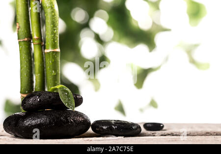 Grean sur des feuilles de bambou zen stones noir pyramide sur fond blanc Banque D'Images