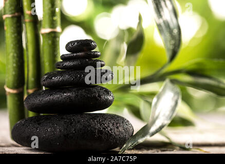 Grean sur des feuilles de bambou zen noir pyramide pierres sur fond de feuilles tropicales Banque D'Images