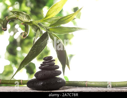 Grean sur des feuilles de bambou zen stones noir pyramide sur fond blanc Banque D'Images